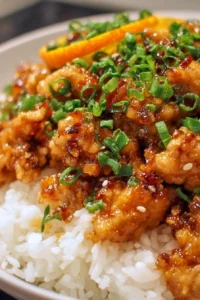 Plate of flavorful ground orange chicken served with vegetables and rice