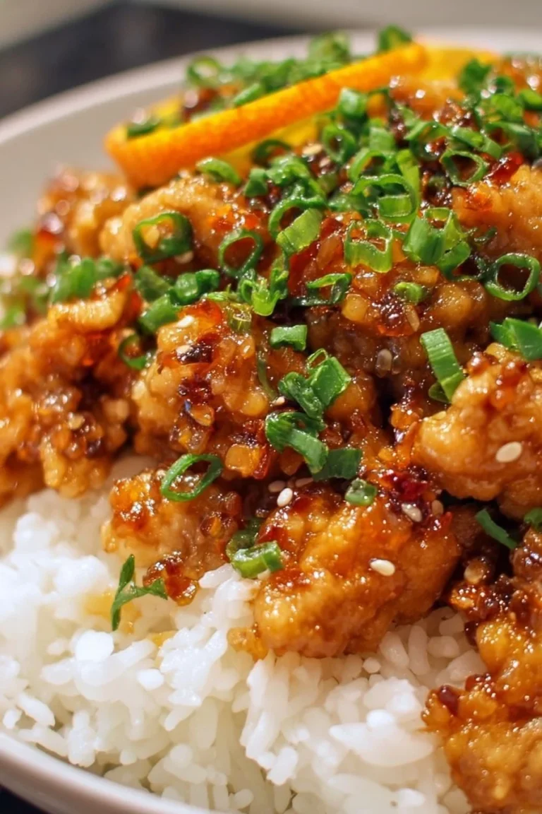 Plate of flavorful ground orange chicken served with vegetables and rice
