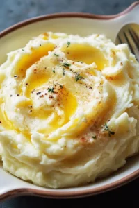 Delicious bowl of cream cheese mashed potatoes garnished with herbs.